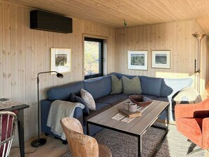 A cozy cabin interior with a blue sofa, a wooden dining table, and framed pictures on the walls. - Cottage by Rauland ski trails with annex (Rauland)
