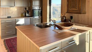 Eine Küche mit Holzschränken, einer Edelstahlspüle und einer großen Kochinsel mit Schüssel.