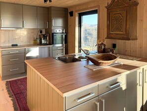 A kitchen with wooden cabinets, a stainless steel sink, and a large island with a bowl. - Cottage by Rauland ski trails with annex (Rauland)