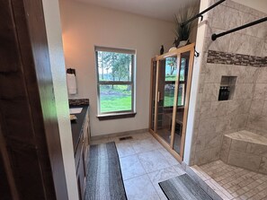 Een badkamer met een douche, een raam en uitzicht op de omgeving.