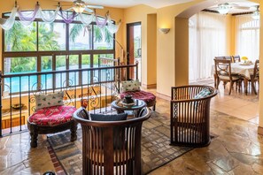 A room with a balcony, a dining area, and a view of a pool and greenery. - Ocean View Tropical Retreat w/ Private Saltwater Pool and Epic Sunset Views! (Potrero)