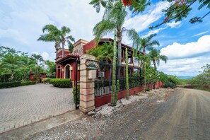 Eine Villa mit gepflasterter Auffahrt, einem verschlossenen Eingang und einem Schild mit der Aufschrift 'Villa Oasis'.