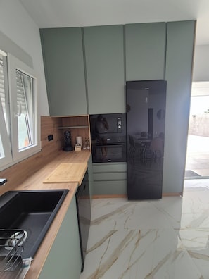 A compact kitchen with a built-in oven, a microwave, and a refrigerator. - Lola's Little House (Conil de la Frontera)