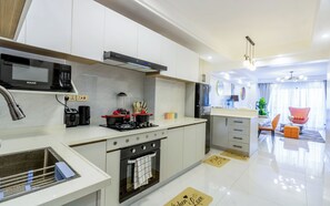 A modern kitchen with white cabinets, a built-in oven, a microwave, and a blender. - Luxurious stay at Vintage -Homes 
3BR (Workspace, Gym, Rooftop & Massage) (Nairobi)