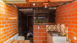 Una cocina compacta con paredes de ladrillo, un lavamanos y una estufa.