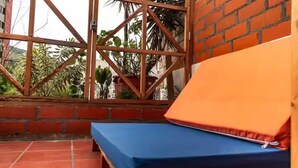 Una habitación con una cama azul, una pared roja y una ventana con marco de metal.