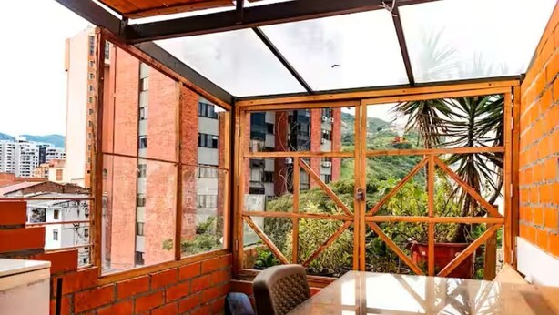 Una habitación con separador de vidrio, una mesa y una silla.