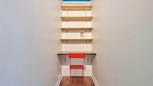 A narrow hallway with wooden shelves and a red chair. - Convention · 15th · Colorful & Bright Studio – managed by Mey Agency (Paris)