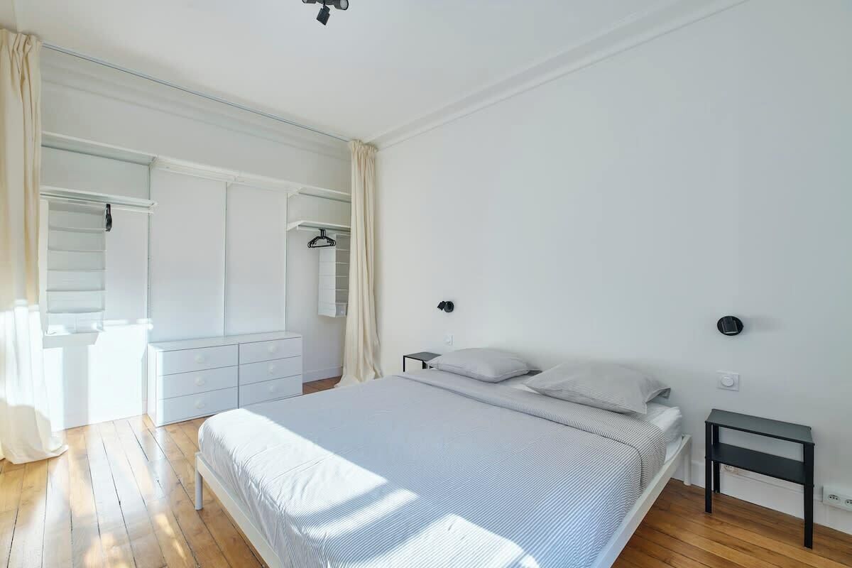Une chambre à coucher avec un lit, des tables de chevet, une armoire et un miroir.