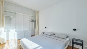 Un dormitorio con cama, mesitas de noche, armario y espejo.