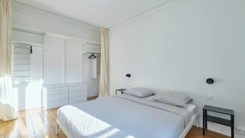 Une chambre à coucher avec un lit, des tables de chevet, une armoire et un miroir.