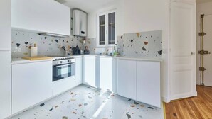 Una cocina moderna con armarios blancos, horno empotrado y ventana.