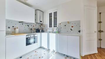 Une cuisine moderne avec des meubles blancs, un four encastré et une fenêtre.