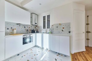 Eine moderne Küche mit weißen Schränken, einem eingebauten Backofen und einem Fenster.