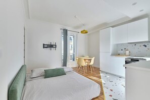 Ein modernes Schlafzimmer mit Bett, einem kleinen Tisch und einer Küchenzeile.