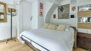 Un dormitorio con cama, armario, espejo y obras de arte en las paredes.