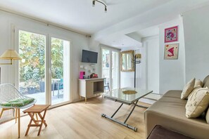 Ein geräumiges Zimmer mit einer Couch, einem Esstisch und einem Fernseher.
