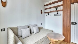 Ein modernes Wohnzimmer mit einer Couch, einem runden Holztisch und Einbauschränken mit Garderobe.