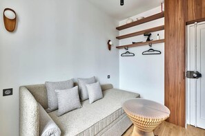 Ein modernes Wohnzimmer mit einer Couch, einem runden Holztisch und Einbauschränken mit Garderobe.
