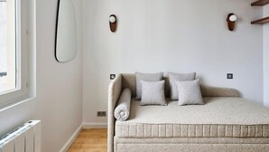 Ein Schlafzimmer mit einem Bett, einem Wandspiegel und zwei Wandleuchten.