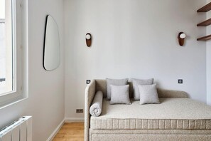 Ein Schlafzimmer mit einem Bett, einem Wandspiegel und zwei Wandleuchten.