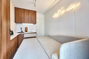 Een moderne kitchenette met een houten kastje, een aanrechtblad en een neonbord aan de muur.