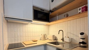 Eine moderne Küche mit weißen Schränken, einer Mikrowelle, einer Kaffeemaschine und einem Toaster.