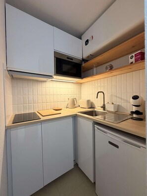 A modern kitchen with white cabinets, a microwave, a coffee machine, and a toaster. - Seignosse Océan, one-bedroom apartment near the beach, quiet, pine forest, family of 4 (SEIGNOSSE)