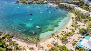 Un resort costero con playa, aguas turquesas cristalinas y varios barcos.