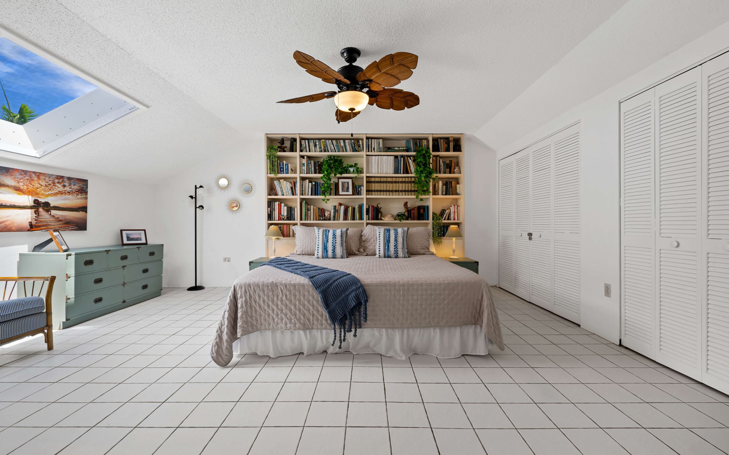 A bedroom with a bed, a bookshelf, a wardrobe, a desk, and a ceiling fan.