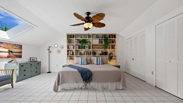 Un dormitorio con cama, estantería, armario, escritorio y ventilador de techo.