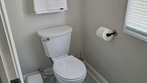 Un baño con inodoro, perchero para toallas, dispensador de papel higiénico y suelo de mármol.