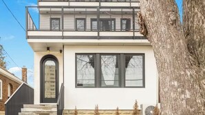 A modern two-story house with a balcony, large windows, and a stone foundation. - Modern Toronto Residence by the Lake - 2BDR (Toronto)
