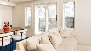 Ein Wohnzimmer mit einem weißen Sofa, einem Holzesstisch und einem blauen Teppich.