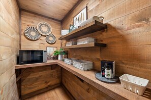 A wooden interior with a microwave, storage bins, and decorative plates on shelves. - Cottage at Fern Cove: Couples • Serene • Hot-Tub • Fire-Pit • Close to Downtown (Blue Ridge)