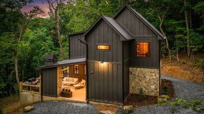 A two-story cabin with a stone foundation, a covered porch, and a grill area. - Enjoy a Cozy Couples Retreat: Serene • Hot-Tub • Fire-Pit • Close to Dtwn + Lake (Blue Ridge)