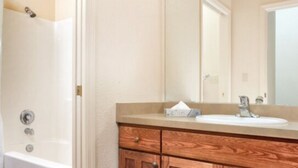 Une salle de bain avec une baignoire, un meuble-lavabo en bois et un miroir.