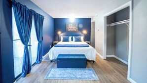 Une chambre à coucher comprenant un lit, des lampes de chevet, un banc, un tapis et une armoire.
