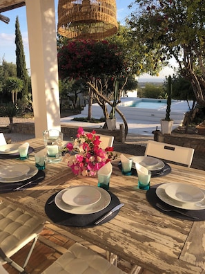 A dining table set outdoors with plates, glasses, and a vase of flowers. - Monte das Oliveiras - Private Villa with Pool (Faro)