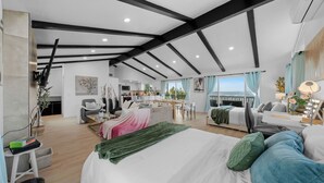 A modern, open-plan living space with a large bed, seating area, and kitchen.