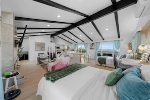 A modern, open-plan living space with a large bed, seating area, and kitchen.