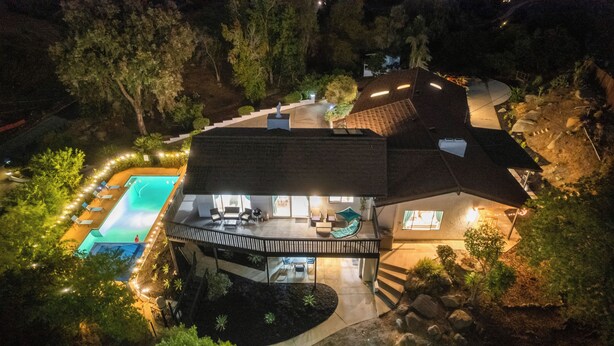 A two-story house with a swimming pool, outdoor seating area, and a covered patio.