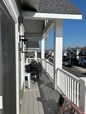 A balcony with outdoor furniture, a railing, and a view of the street and houses.