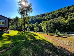 A house with a grassy yard, trees, and a river in the background.