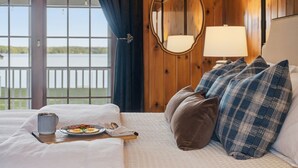 Ein Hotelzimmer mit Bett, einem Esstisch mit Frühstück, Seeblick und einem Spiegel an der Wand.