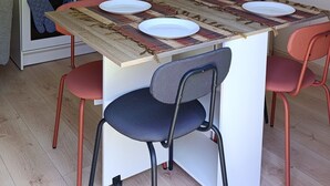 Kompakti keittiö, jossa on keskeinen keittiösaareke, kaksi tuolia, pieni uuni ja kahvinkeitin.