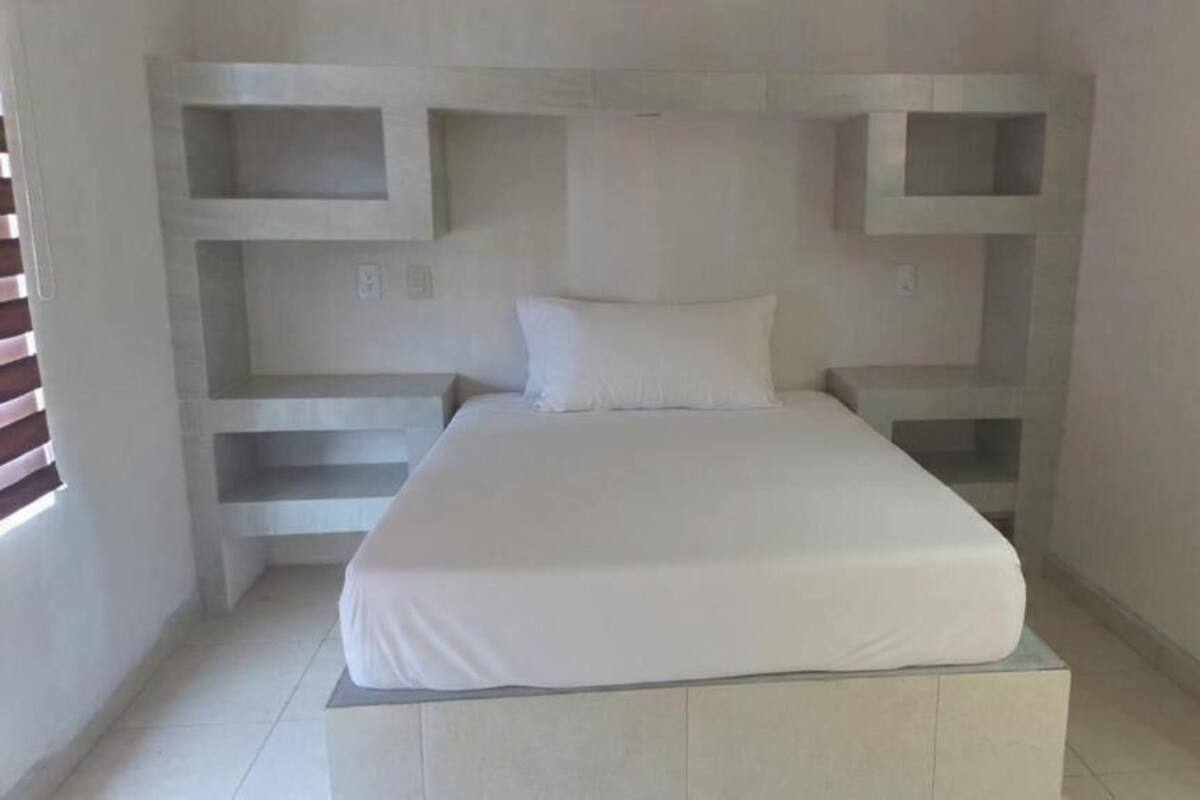 Un dormitorio con cama, estanterías empotradas y ventana.