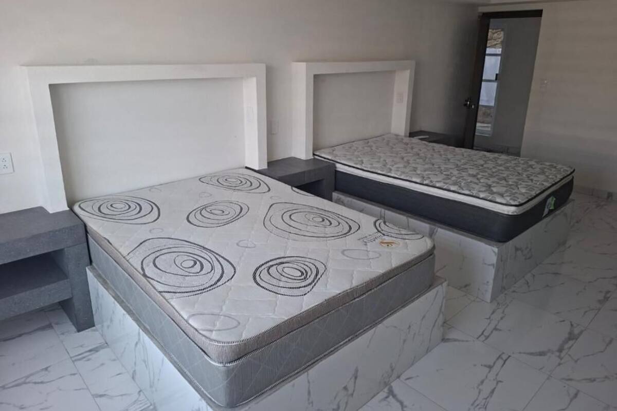 Un dormitorio con dos camas, piso de mármol y una puerta al fondo.