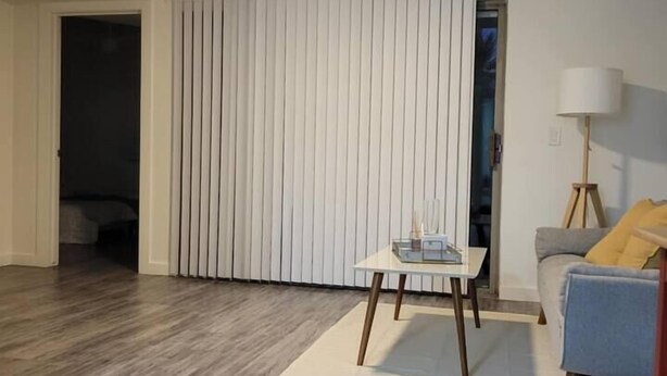 Une pièce avec un ventilateur de plafond, une porte coulissante, une table avec une lampe et un canapé.