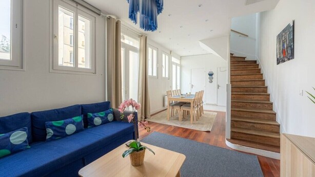 A modern living room with a blue sofa, a wooden coffee table, and a staircase leading to an upper floor. - Blue House - Parking - Downtown (Reims)